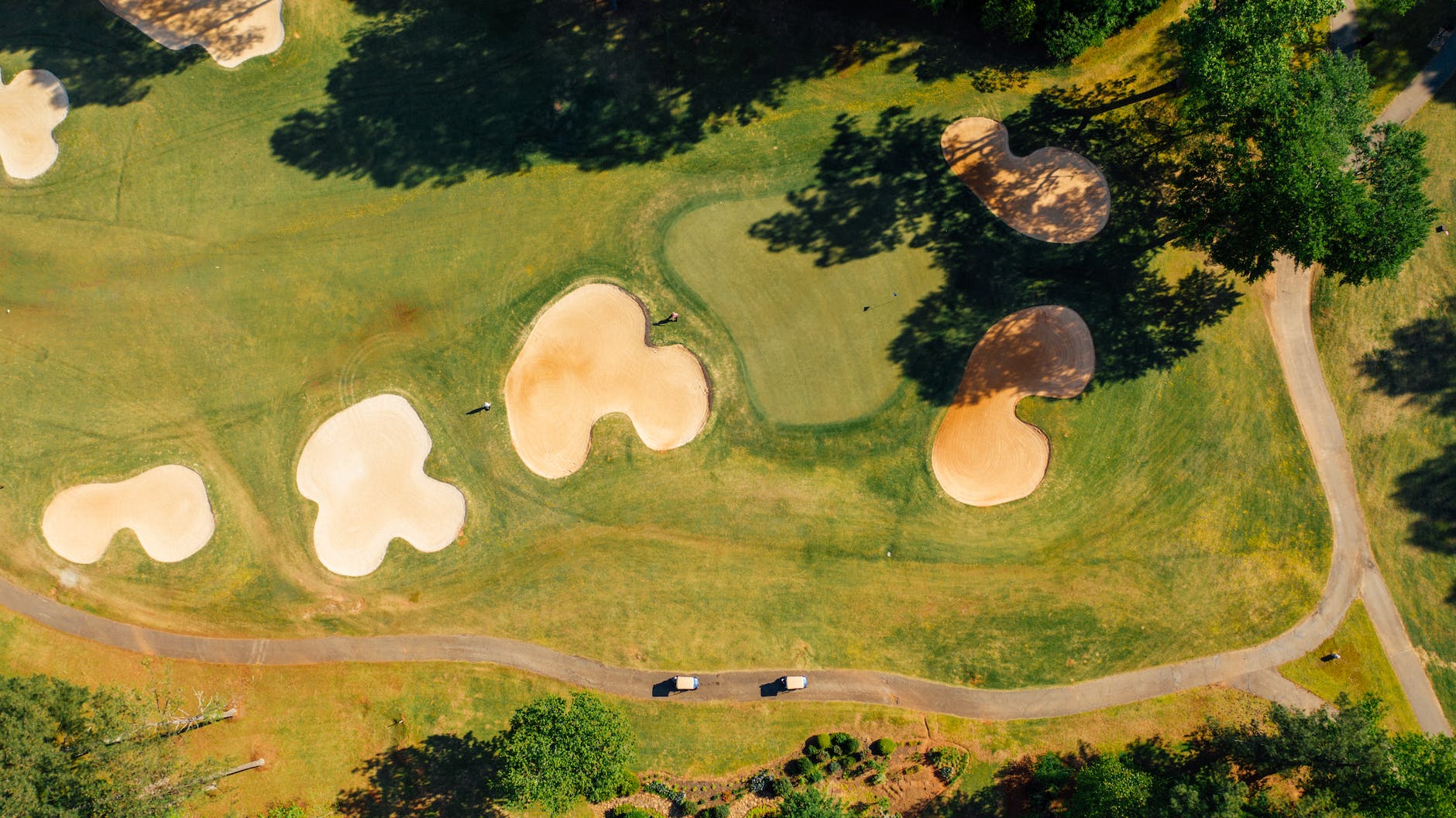 green golf course with bunkers near wavy road